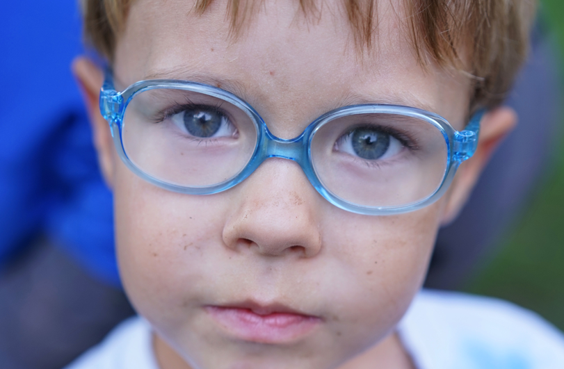 young boy with blonde hair and blue glasses